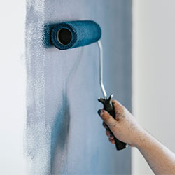 Una persona pintando la pared con pintura de decoración azul